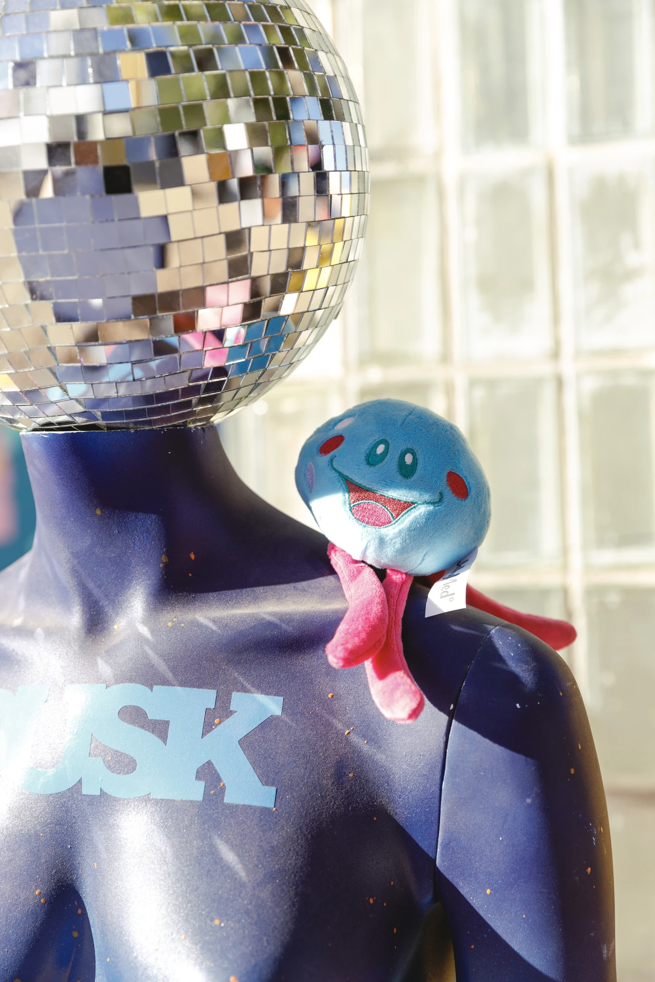 Rori perched beside a mirrored disco-ball head at DUSK