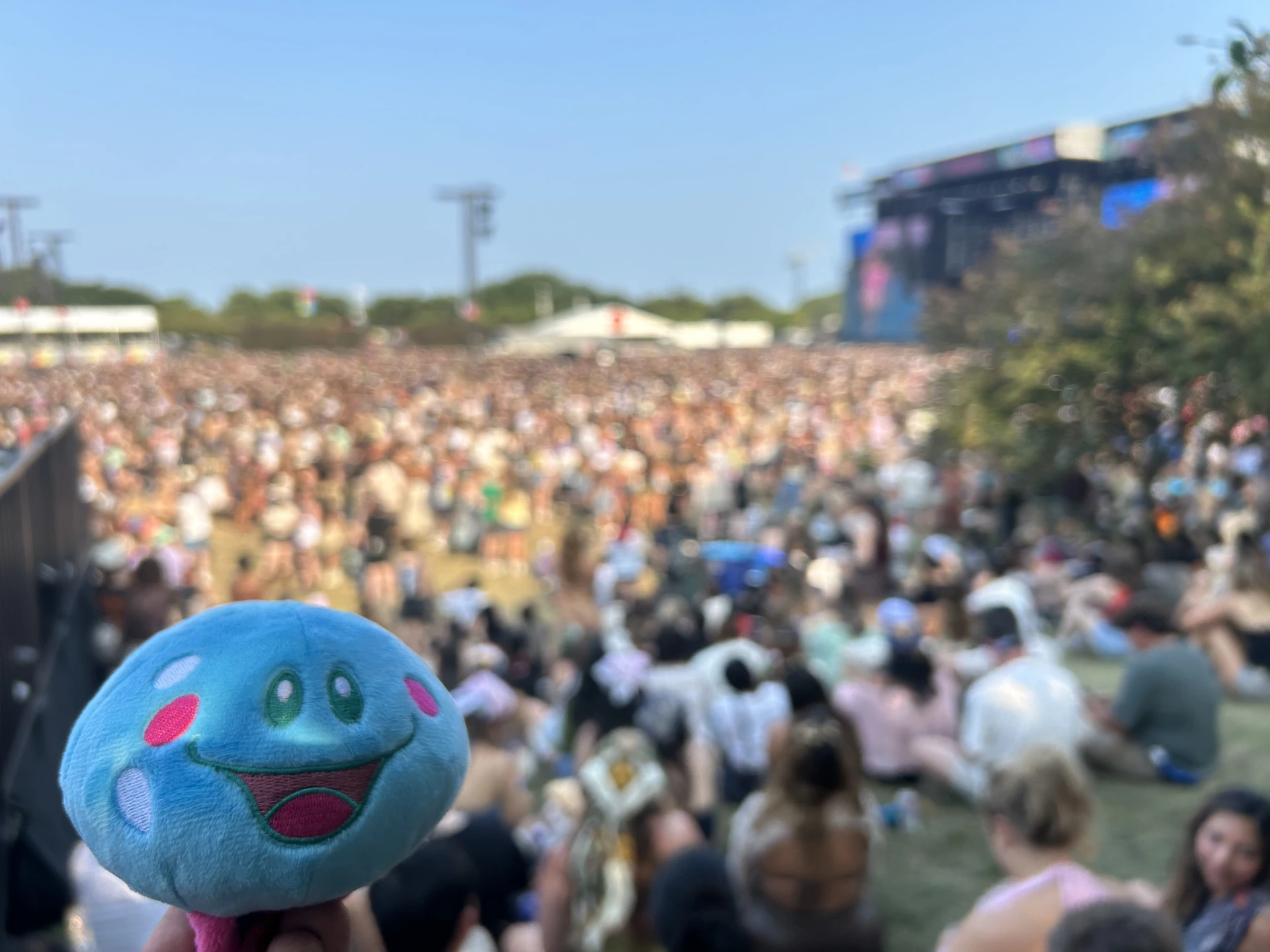 A blue Rori plush overlooking the festival crowd